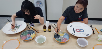 김해도예협회 작가들이 제작한 초벌도자기에 참여자들이 그림을 그리고 있다.