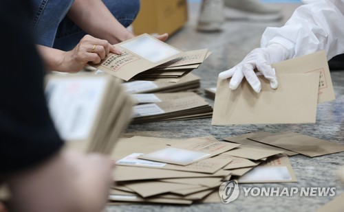 제8회 전국동시지방선거 사전투표 이틀째인 28일 서울 용산구의회에 마련된 사전투표소에서 관계자들이 관외 투표용지를 정리하고 있다.