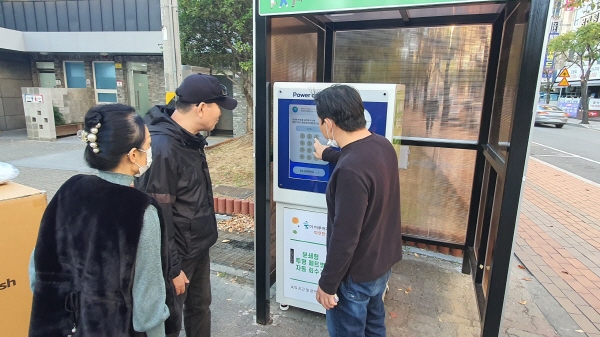 ﻿김해시 관계자가 거북공원에 설치된 투명페트병 자동수거기 사용법을 안내하고 있다.