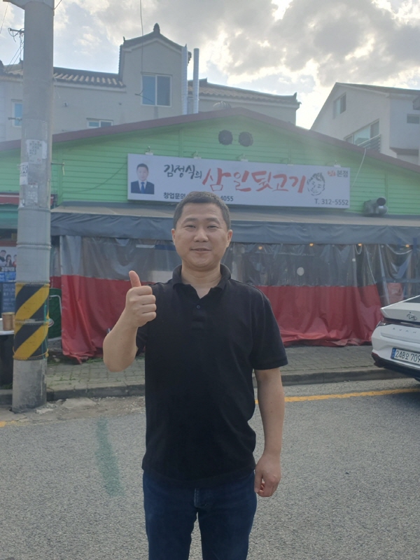﻿김정식 대표가 음식점 앞에서 엄지를 치켜세우며 김해 뒷고기 전국화에 자신감을 보이고 있다.