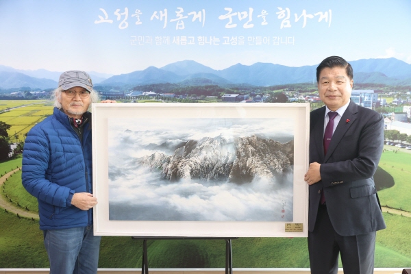 ﻿고성 출신 목재 김영화 화백이 22일 고성군에 한국화 작품을 기탁하고 이상근 군수와 기념사진을 찍고 있다.