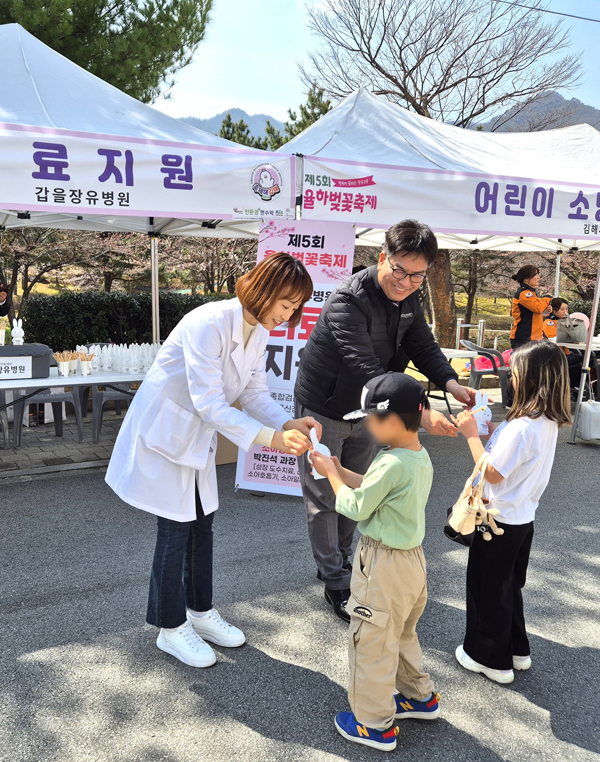 ﻿'제5회 율하카페거리 벚꽃축제'에서 갑을장유병원 관계자가 부스를 방문한 어린이들에게 토끼저금통을 선물로 제공하고 있다.